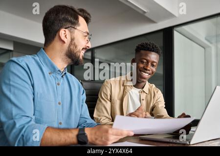 Due dipendenti uomini felici e impegnati che controllano i documenti in ufficio durante la riunione. Foto Stock