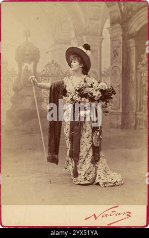 Sarah Bernhardt interpreta Floria Tosca nell'atto i di Sardou 'Tosca', negative 1887; stampa e monta dopo il 1889. Informazioni aggiuntive: Una donna, Sarah Bernhardt, in un elegante cappello e abito, con un grande bouquet di fiori, in piedi di fronte a un elaborato sfondo dipinto. Foto Stock