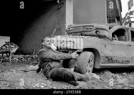 Beirut, Beirut, Libano. 13 dicembre 2024. Un inquilino libanese del devastato quartiere di basta, colpito da incursioni aeree durante i due mesi di guerra totale tra Israele e militanti di Hezbollah, si siede vicino al relitto di un'auto durante un raduno di residenti della zona per alzare la voce chiedendo al governo un risarcimento per decine di edifici devastati e per trovare rifugio per le famiglie che hanno perso le loro case. (Credit Image: © Marwan Naamani/ZUMA Press Wire) SOLO PER USO EDITORIALE! Non per USO commerciale! Foto Stock