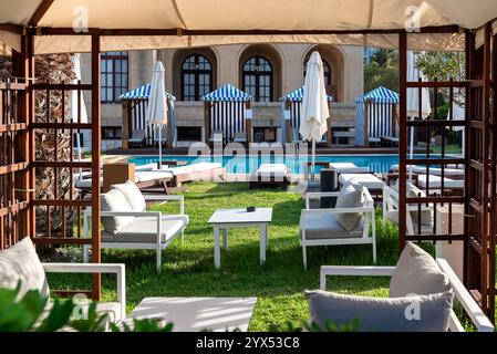 Sdraio sull'erba vicino alla piscina in un lussuoso cortile dell'hotel Foto Stock