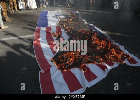 Sanaa, Yemen. 13 dicembre 2024. Le bandiere STATUNITENSI e israeliane bruciano durante una manifestazione di solidarietà con "il popolo di Gaza”, nel mezzo del conflitto in corso tra Israele e Hamas nella Striscia di Gaza. Crediti: Osamah Yahya/dpa/Alamy Live News Foto Stock