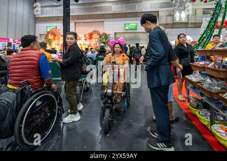 Una donna con disabilità, con una sedia a rotelle elettrica, vista passare dai visitatori, al Thailand Friendly Design Expo 2024, al Bangkok International Trade and Exhibition (BITEC). Il Thailand Friendly Design Expo 2024 mira a creare una società più inclusiva e sostenibile per gli anziani e le persone con disabilità in Thailandia attraverso il design e la tecnologia. Fondato da Krisana Lalai, giornalista tailandese e attivista per i diritti umani, l'evento promuove l'accessibilità in vari settori. Dopo un incidente d'auto nel 1997, Krisana dedicò la sua vita a sostenere l'inclusione Foto Stock