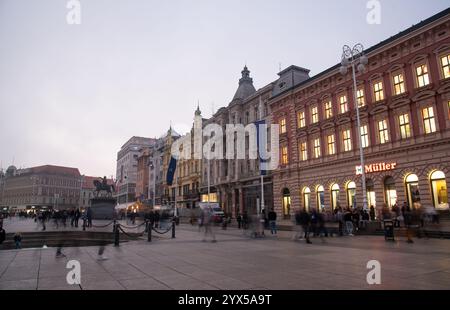 Zagabria, Croazia, ottobre 31 2024: Persone che camminano e si godono piazza Ban jelacic a zagabria, croazia, con un tram che passa al tramonto Foto Stock