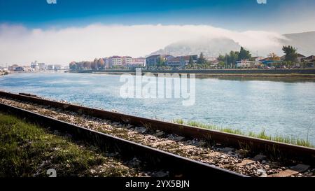 Piccola città su una collina avvolta dalla nebbia con la ferrovia di fronte Foto Stock