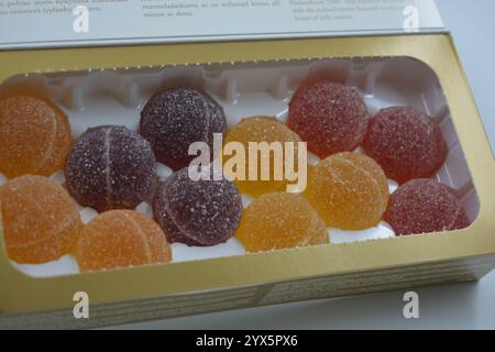 Caramelle finlandesi originali in gelatina sotto forma di palline rotonde ricoperte di zucchero bianco. Le caramelle gommose gialle, arancioni, ciliegine rosse sono in confezioni bianche. Foto Stock