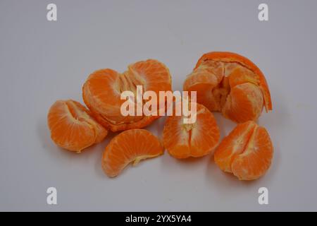 Cibo sano e sano, frutta fresca. Due bellissimi mandarini arancioni con bucce sbucciate si trovano su uno sfondo di plastica bianco. Foto Stock