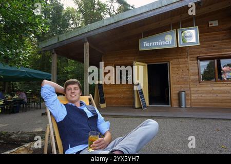Il giovane beve apfelwein una bevanda tradizionale di sidro seduto su una sedia all'esterno del ristorante, Hesse, Germania, Europa. Foto Stock