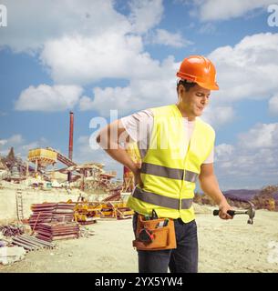 Operaio edile che gli sta soffrendo la schiena in un cantiere edile Foto Stock