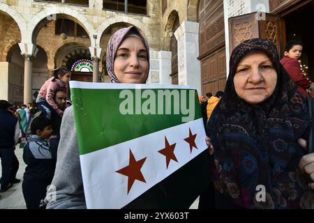 Centinaia di persone si riuniscono per festeggiare con le "bandiere della rivoluzione siriana" dopo aver eseguito la preghiera del primo venerdì dopo il crollo del regime di Baath di 61 anni in Siria e la fine del governo della famiglia Assad a Damasco, in Siria, il 13 dicembre 2024. Migliaia di giubilanti siriani si sono riuniti anche fuori da una moschea di riferimento nella capitale Damasco per celebrare durante le preghiere del primo venerdì dall'estromissione di Assad l'8 dicembre. Foto di FADEL ITANI/UPI. Crediti: UPI/Alamy Live News Foto Stock