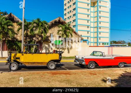 Due auto, una gialla e una rossa, sono parcheggiate l'una accanto all'altra in una strada. L'auto gialla è una barca, e l'auto rossa è un'auto d'epoca. La scena lo è Foto Stock