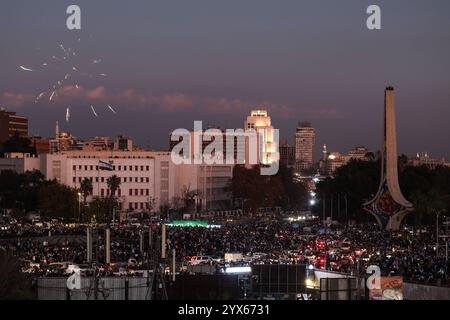 I fuochi d'artificio illuminano il cielo notturno mentre la gente si riunisce in Piazza Omayyad per celebrare il crollo del regime di Baath di 61 anni e la fine dell'era della famiglia Assad a Damasco, in Siria, il 13 dicembre 2024. Migliaia di giubilanti siriani si sono riuniti anche fuori da una moschea di riferimento nella capitale Damasco per celebrare durante le preghiere del primo venerdì dall'estromissione di Assad l'8 dicembre. Foto di Omar Haj Kadour/UPI credito: UPI/Alamy Live News Foto Stock