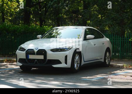 Bucarest, Romania - 22 luglio 2024: Vista frontale della BMW i4 edrive40 auto elettrica bianca parcheggiata nel parcheggio di fronte al recinto del parcheggio Foto Stock