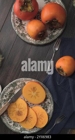 L'autunno soffia su piatti vintage, uno tagliato con un coltello, l'altro intero, su un tavolo di legno scuro con un tovagliolo e forchette blu Foto Stock