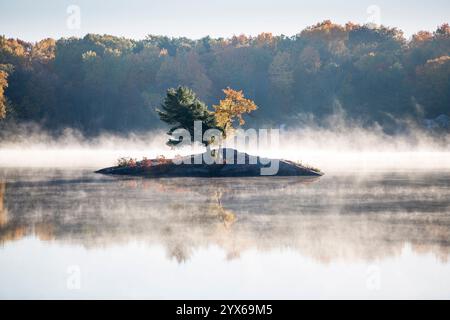 Una piccola isola fatta di roccia su un lago calmo. Foto Stock