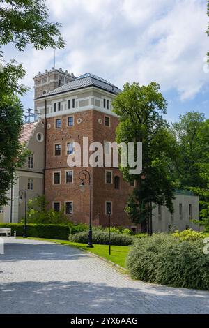 Edificio storico in mattoni con un'aggiunta architettonica moderna circondato da vegetazione lussureggiante e sentieri acciottolati in una giornata di sole Foto Stock