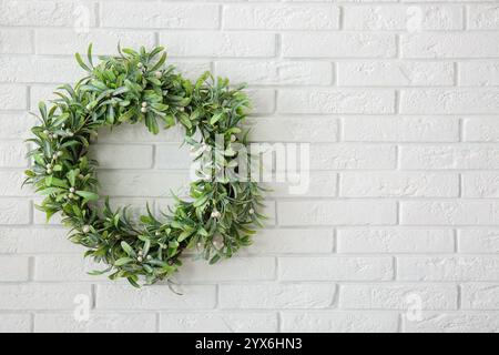 Corona di vischio natalizio su un muro di mattoni bianchi Foto Stock