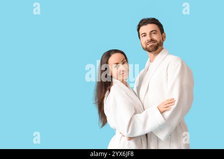 Una coppia adorabile in accappatoi abbracciati su sfondo blu Foto Stock