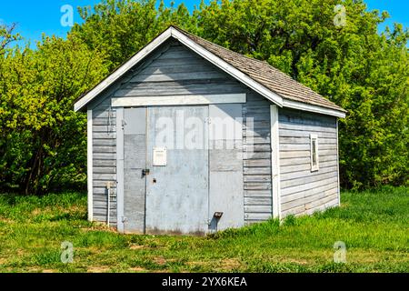 Un piccolo edificio in legno vecchio stile con un tetto inclinato. Il tetto è coperto di muschio e l'edificio sembra essere abbandonato Foto Stock