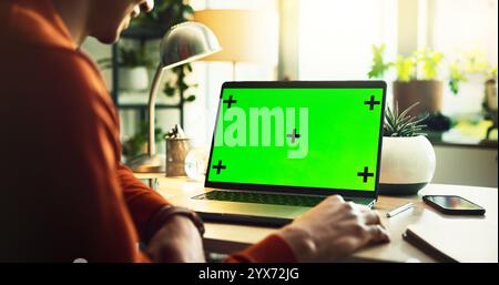 Persona, libero professionista e laptop con schermo verde o mockup per pubblicità online, marketing o software UI presso l'ufficio domestico. Primo piano, utente o computer Foto Stock