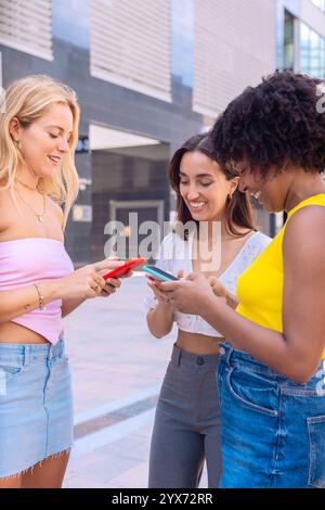 Tre amici entusiasti che guardano uno smartphone all'aperto. Verticale Foto Stock