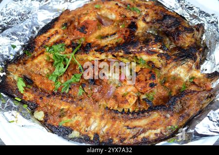 Pesce Sinjari Tilapia, il pesce viene aperto e grigliato con olio e limone o cotto e cotto al forno con verdure prezzemolo, pomodoro, cipolla e sma Foto Stock