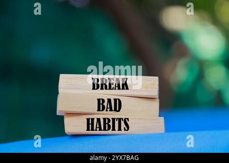 Infrangere il simbolo delle cattive abitudini. Le parole concettuali rompono le cattive abitudini sui blocchi di legno. Splendido sfondo blu e sfocato. Rompere il concetto di cattive abitudini. Copia spazio. Foto Stock