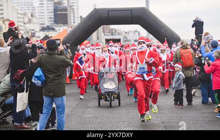 Brighton Regno Unito 14 dicembre 2024 - i partecipanti che partecipano a quest'anno Brighton Santa Dash lungo il lungomare di Hove raccogliendo fondi per la beneficenza per bambini Rockinghorse in una mattinata fresca e noiosa lungo la costa meridionale : Credit Simon Dack / Alamy Live News Foto Stock