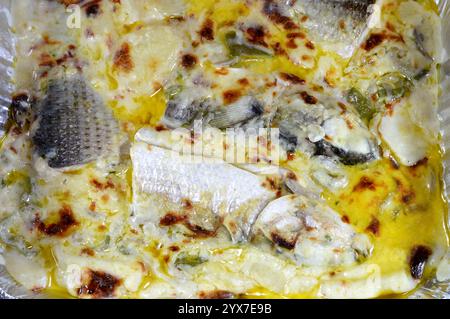 Pesci triglia al forno con salsa bianca cremosa, pezzi e fette di patate, ghee, erbe aromatiche e spezie di pesce, cotti al forno, cucina di mare a base di mulle Foto Stock