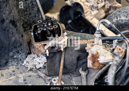 Parti del motore, chiavi e straccio sporco smontati sono appoggiati su una superficie ruvida durante la manutenzione. Grease and Grime raccontano una storia di duro lavoro e repa Foto Stock