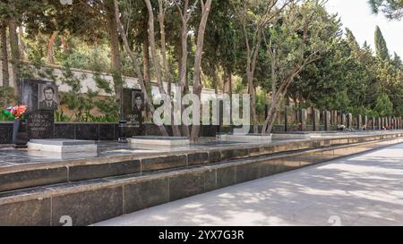 Baku, Azerbaigian - 6 maggio 2024: Corsia dei martiri a Baku, Azerbaigian, onora i soldati caduti di guerra. Fiancheggiato da tombe con ritratti commemorativi, il viale solenne è circondato da alberi lussureggianti Foto Stock
