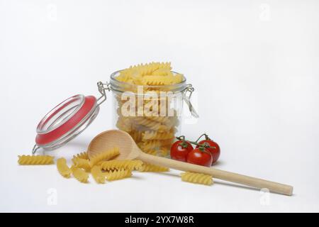 Pasta, varietà "Fusili" in contenitore di vetro con cucchiaio da cucina Foto Stock