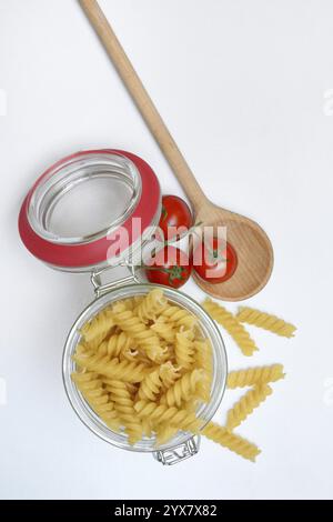 Pasta, varietà "Fusili" in contenitore di vetro con cucchiaio da cucina Foto Stock