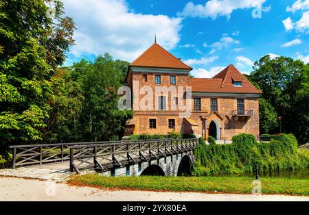 Oporow, Polonia - 17 agosto 2024: Cavalieri medievali in mattoni gotici castello di Oporowskich con fossato bagnato e ponte levatoio all'interno del parco storico nel villaggio di Oporow Foto Stock