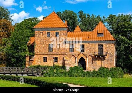 Oporow, Polonia - 17 agosto 2024: Cavalieri medievali in mattoni gotici castello di Oporowskich con fossato bagnato e ponte levatoio all'interno del parco storico nel villaggio di Oporow Foto Stock