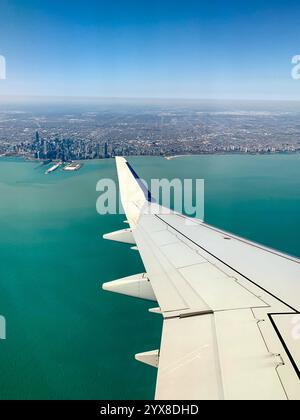 Una splendida vista aerea di una costa turchese e di un paesaggio urbano dalla finestra di un aereo, che offre un momento di viaggio sereno e mozzafiato. Foto Stock