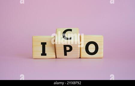 Simbolo ICO e IPO. Cubi di legno con parole ICO - offerta iniziale di monete e IPO - offerta pubblica iniziale. Bellissimo sfondo rosa. Concetto di business Foto Stock