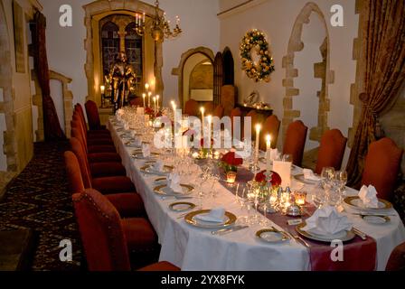 Cena a lume di candela, atmosfera da banchetto formale con posti a sedere e candele illuminate preparate, cena lunga con tavolo in un ambiente elegante e formale con decorazione a corona di Natale Foto Stock