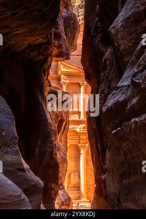 La facciata scolpita dell'edificio del Tesoro o al-Khazneh nell'antica città di Petra in Giordania, vista attraverso la stretta gola Foto Stock