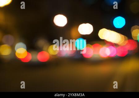 bokeh astratto di luce, luci sfocate e sfocate delle auto durante gli ingorghi su uno sfondo stradale bagnato e piovoso Foto Stock