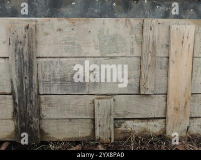 una vecchia recinzione bassa fatta di tavole di diverse dimensioni che si abbattono casualmente come una struttura in legno ruvido unica invecchiata dagli effetti del tempo Foto Stock