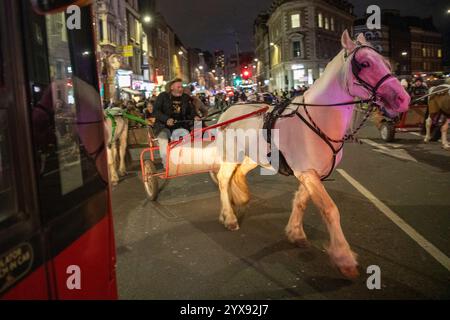 Londra, Regno Unito, 14 dicembre 2024. Un autobus si ferma davanti a un cavallo e a un carro. Centinaia di zingari e viaggiatori guidano cavalli e carri tradizionali attraverso le strade di Londra durante l'annuale viaggio natalizio. Crediti: James Willoughby/ALAMY Live News Foto Stock