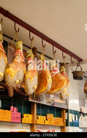 Cremona, Italia - 15 novembre 2020 prosciutti di parma stagionati appesi ad uncini in una tradizionale gastronomia italiana, che mette in mostra la gastronomia italiana Foto Stock