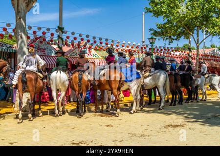 Il paesaggio di Siviglia. I cavalieri socializzano di fronte alle tende alla fiera di aprile di Siviglia, Feria de Abril, un famoso festival in Spagna. Foto Stock