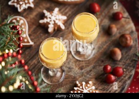 Due bicchieri di Eiercognac con biscotti natalizi di pan di zenzero e rami di abete rosso Foto Stock