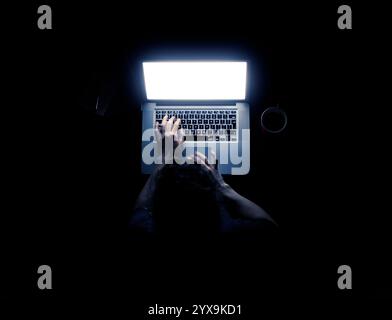 Donna che utilizza un computer portatile al buio con le sue mani illuminato dalla schermata del computer isolati su sfondo nero Foto Stock