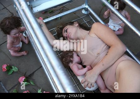 Londra, Inghilterra, Regno Unito. 14 dicembre 2024. Un essere umano è limitato in una gabbia e succhia il suo bambino come parte di una controversa installazione artistica. L'installazione "The Human Farrowing Crate", situata all'esterno della Saatchi Gallery di Chelsea, a Londra, riunisce una collaborazione tra Stephanie Lane e l'Animal Justice Project, che fonde arte e attivismo. Crediti: ZUMA Press, Inc./Alamy Live News Foto Stock