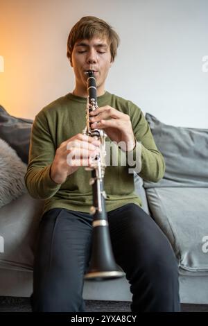 Suonatore di clarinetto. Clarinettista che suona flauto strumento a fiato a casa. Il tizio gioca a oboe Foto Stock