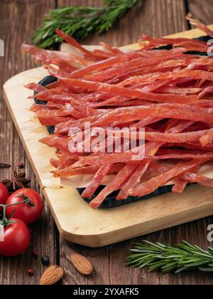 Cannucce di carne di maiale affumicata per la birra su un vassoio di legno con verdure e noci sul tavolo Foto Stock