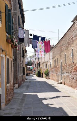 VENEZIA, ITALIA - 19 LUGLIO 2024: Tipica vista sulla strada laterale con abiti appesi nei quartieri esterni di Venezia. Foto Stock