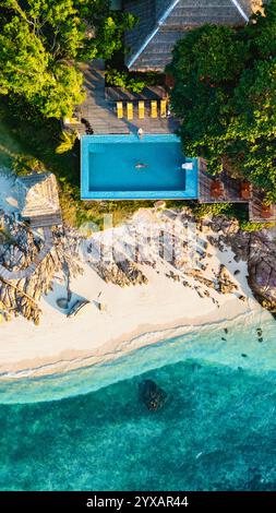 Affacciato sulla splendida costa dell'isola di Koh Munnork, le acque azzurre si infrangono dolcemente sulle coste sabbiose. Il relax ti attende vicino a una scintillante piscina, circondata da una vegetazione lussureggiante e da un sole vibrante. Foto Stock